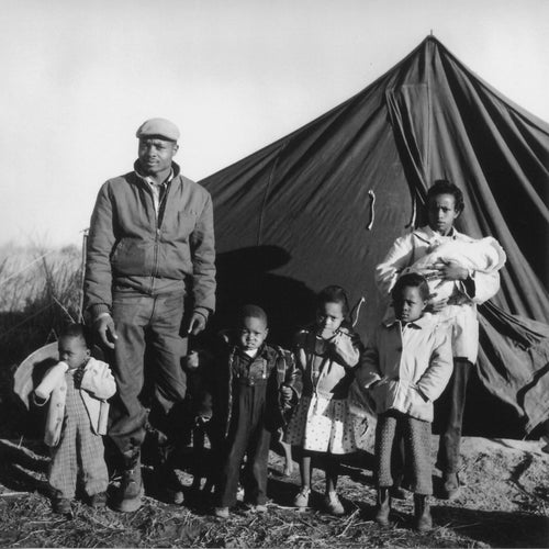 In the late 50's and early 60's, a push was made by the Student Non-Violent Coordinating Committee, and other civil rights organizations, to expand their work outside of urban centers. So called "Freedom Summers" were organized, where town halls, sit-ins, voter registrations drives, and similar activities were organized. As a response to this, the white residents of Fayette and Sumner County (TN) organized a blacklist of African American residents who participated in these events. Those on the list were not allowed to get much needed loans from banks to finance their farmwork. This eventually forced them off their land, and many took up residence in the "Freedom Village" tent city on farmer Shepard Towles' land. Here we see the Mason family outside their tent in Freedom Village.