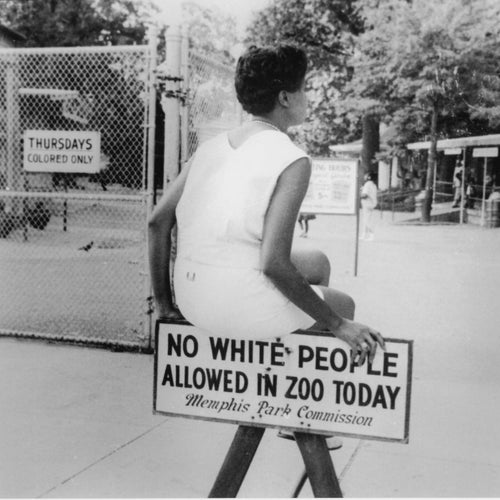 During segregation, Black families could visit the Memphis Zoo only one day a week — on what was called ‘Colored Day.’ Here, JoAnn  Mayo Osboune takes a seat on the sign placed outside the zoo, highlighting the reality of Jim Crow in the South.